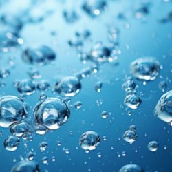 Primer plano de numerosas pequeñas burbujas de aire suspendidas en un líquido azul transparente que recuerda al agua hidrogenada. Las burbujas varían de tamaño y captan y reflejan la luz, creando un efecto brillante contra el fondo liso.