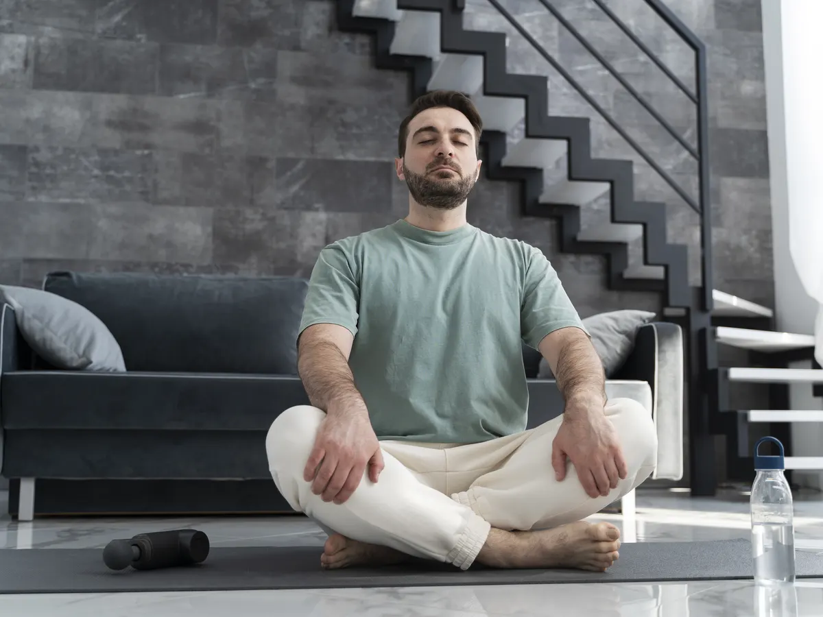 Hombre meditando sentado en una esterilla en su salón