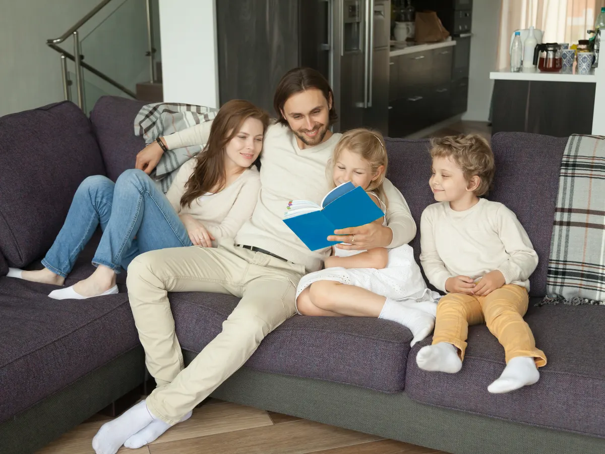Familia leyendo un libro juntos en el sofá